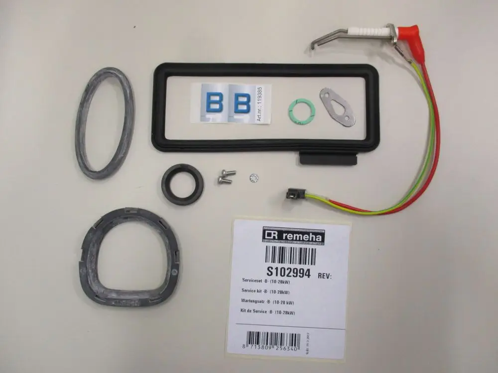 Remeha Service-Set bestehend aus verschiedenen Dichtungen, Schrauben, einem Elektroanschluss und einem Modul für Wartungsarbeiten. Komponenten auf hellem Hintergrund angeordnet.